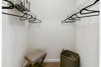 a closet with a chair and shoe racks on the wall